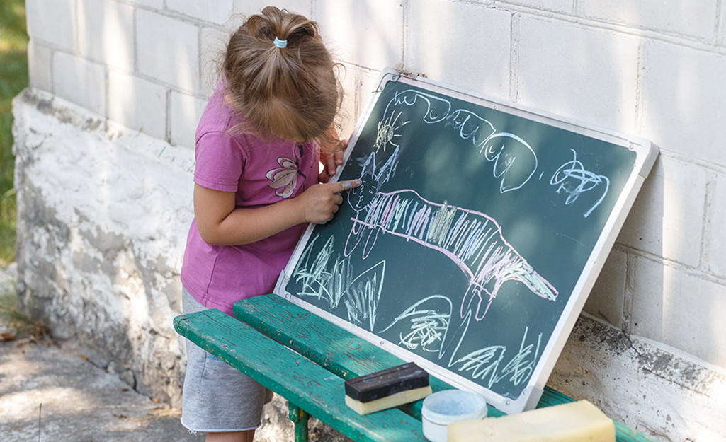 A child drawing on a chalkboard outside.