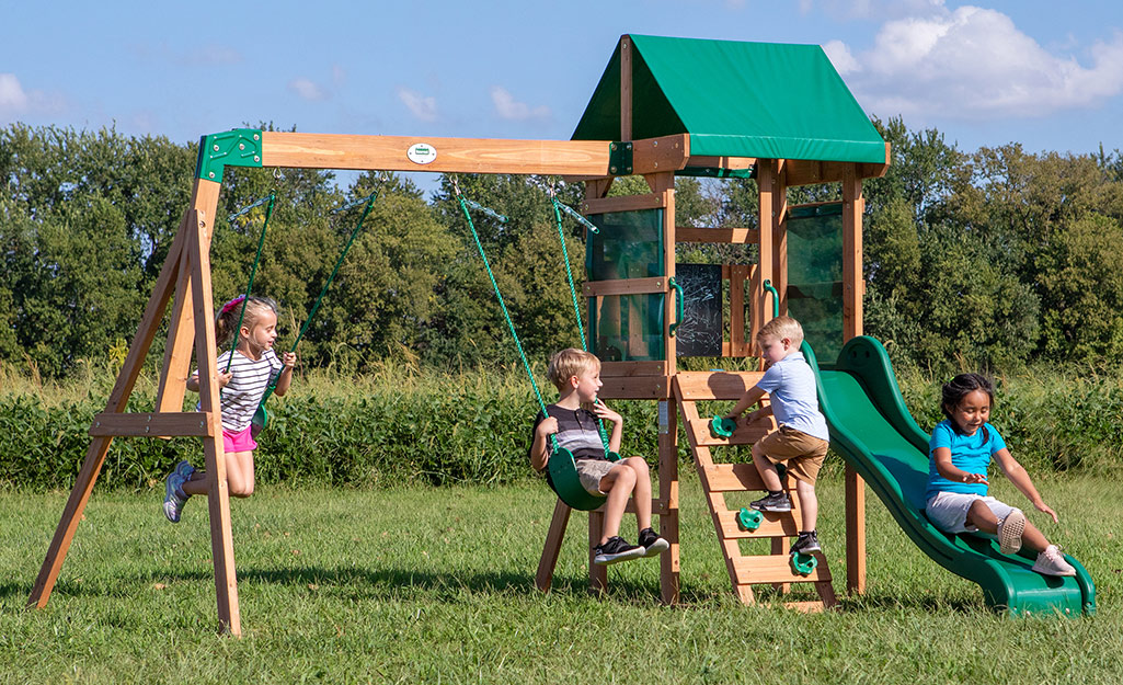 Children playing on a wood swing set.