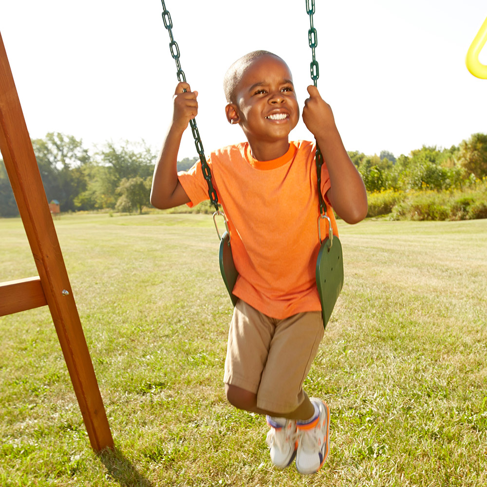 A boy swings on a swing set. A boy swings on a swing set.