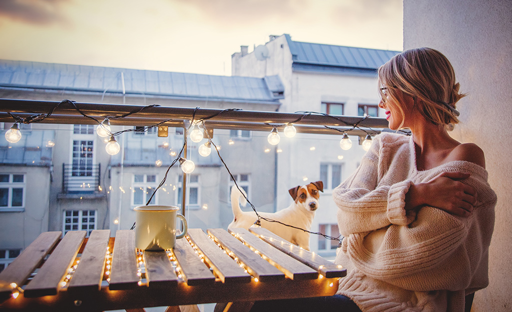 Woman admiring her lighted patio table and balcony lights.