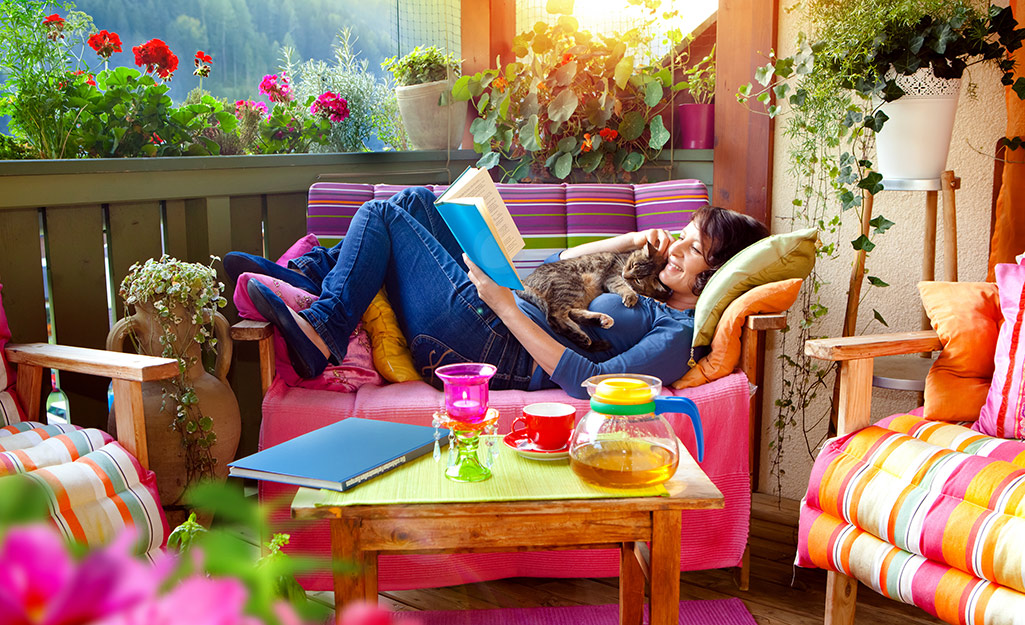 Woman sitting on colorful patio furniture on a balcony.