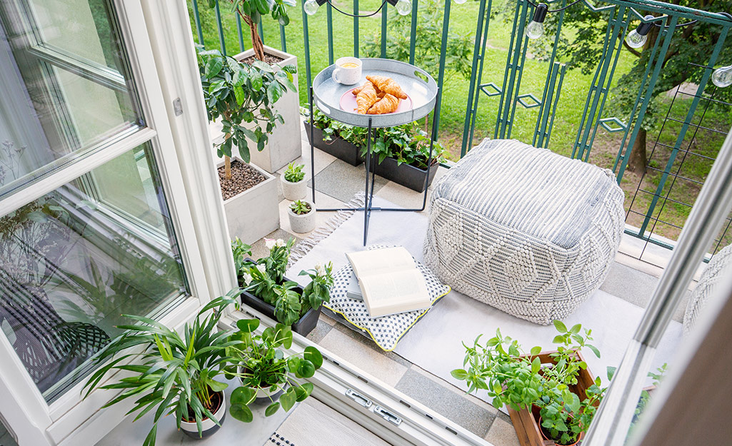 Outdoor pouf and metal table placed on a small apartment balcony.