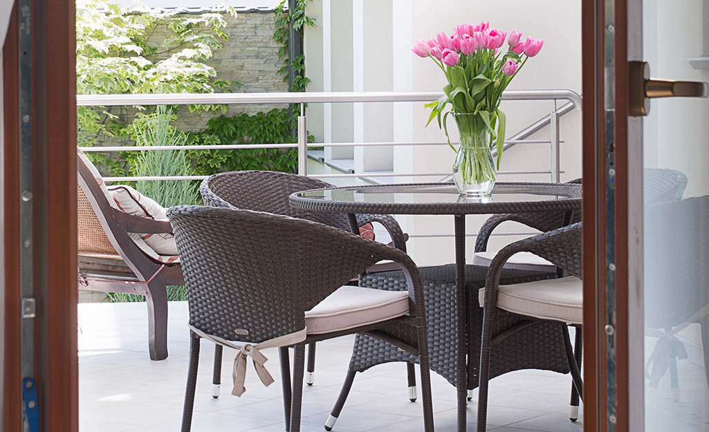 Pink tulips sitting on an outdoor wicker dining table.