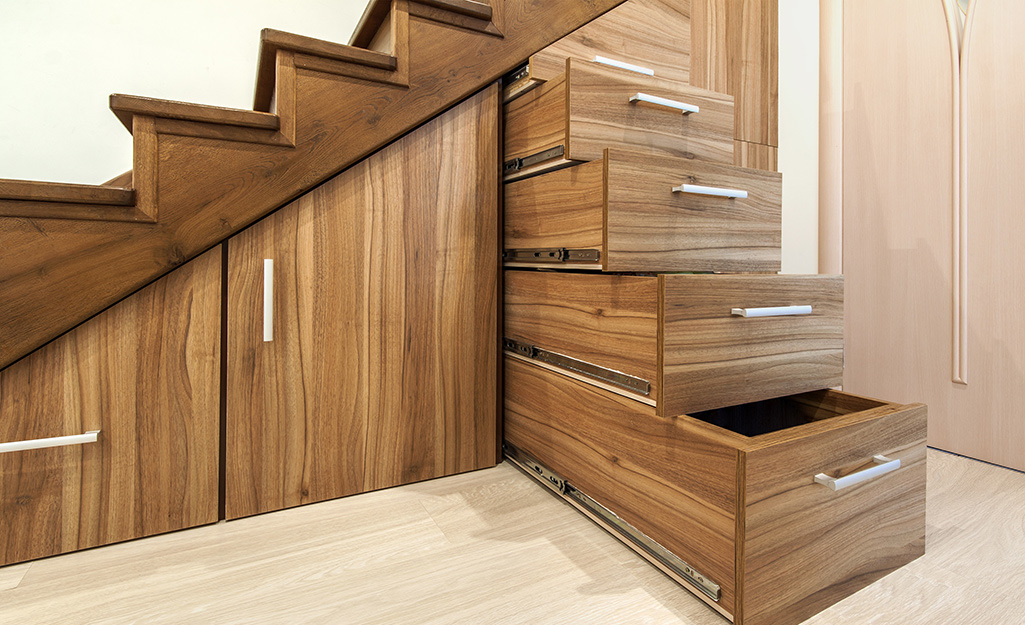 Custom cabinets and drawers under basement stairs are used for storage. 
