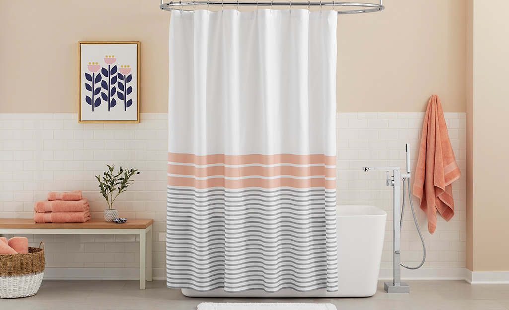 A striped shower curtain surrounding a modern bath tub.