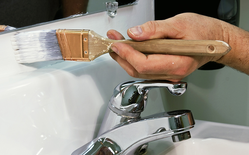 A person painting a vanity in a bathroom.