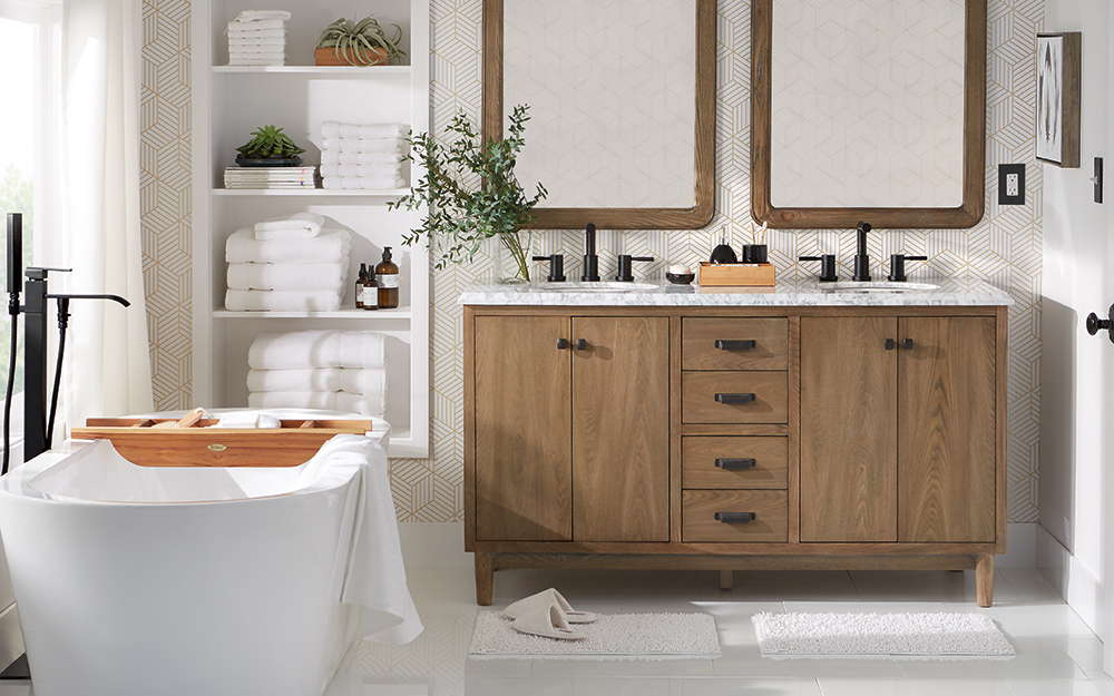 A clean, modern bathroom with a tub, a cabinet, a double sink vanity and two mirrors.