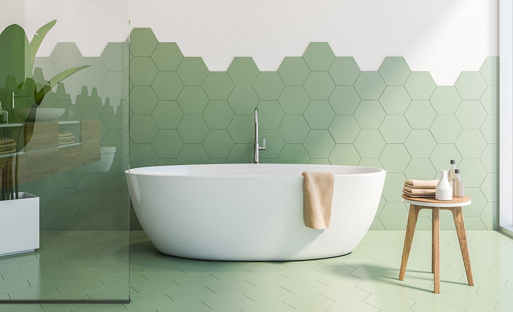 Green hexagon tile artfully installed behind a soaking tub.