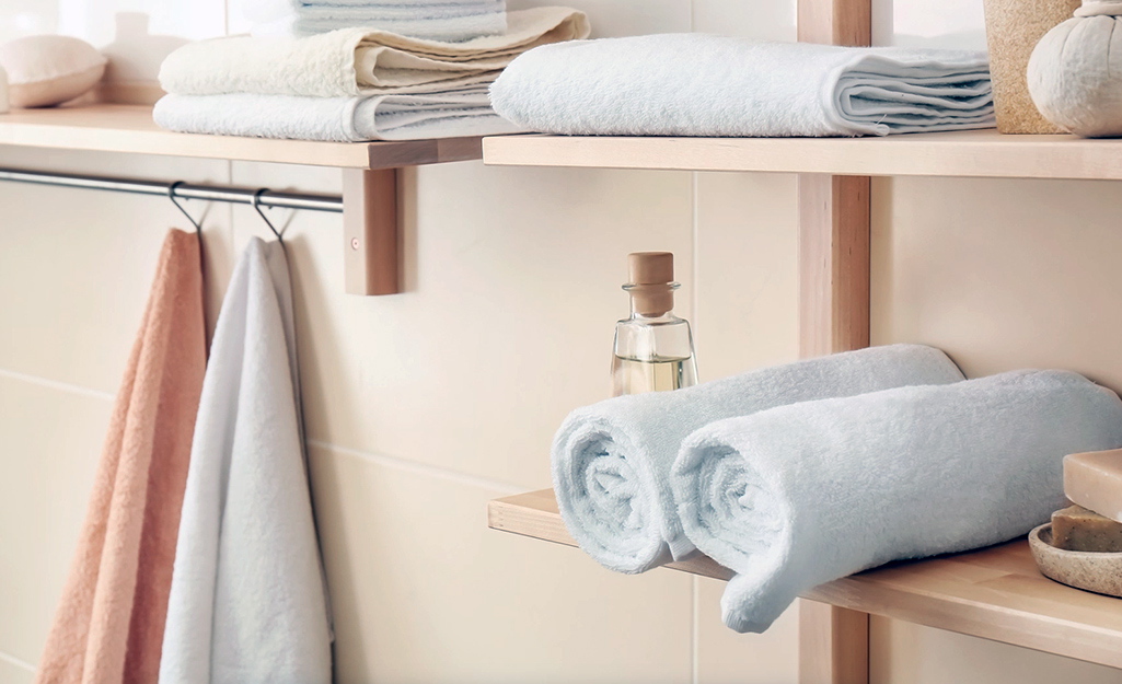 Towels rolled up and placed on an open shelf.
