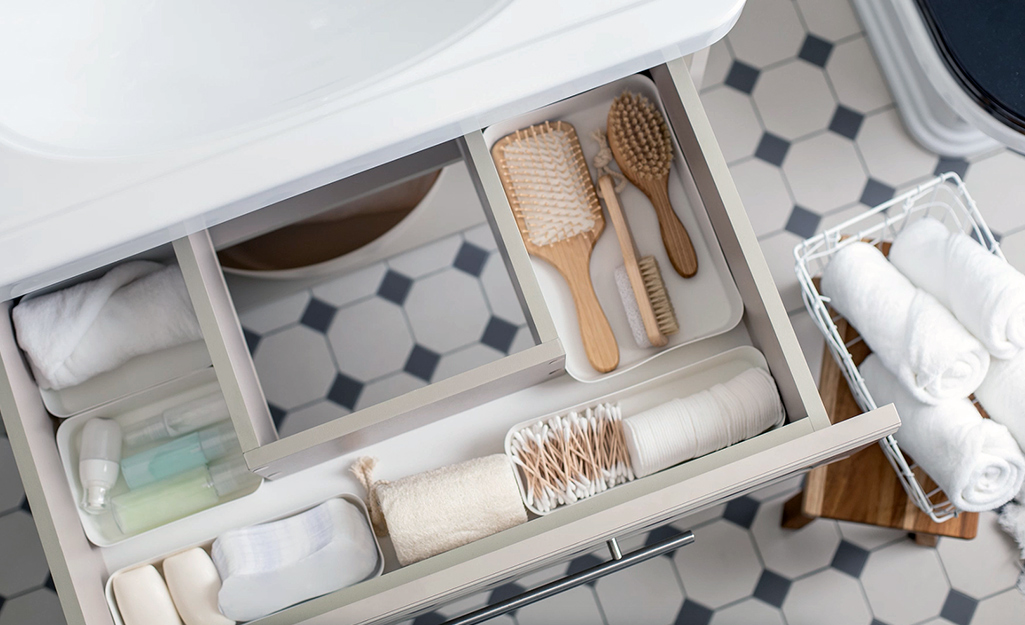 A bath vanity drawer containing an organizer filled with toiletries.