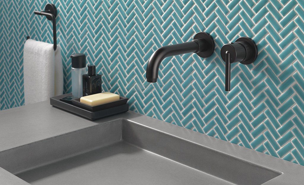 Green bathroom wall tiles in a herringbone pattern.