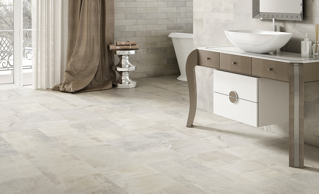 Brushed pattern floor and wall tiles in a large bathroom.