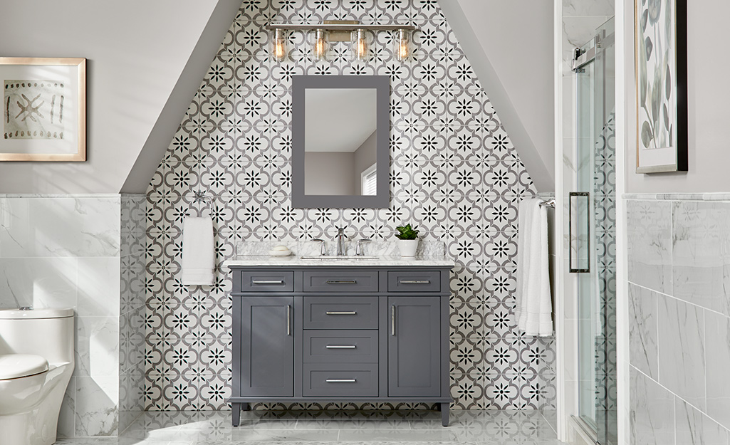 A bathroom with gray solid and patterned tiles. 