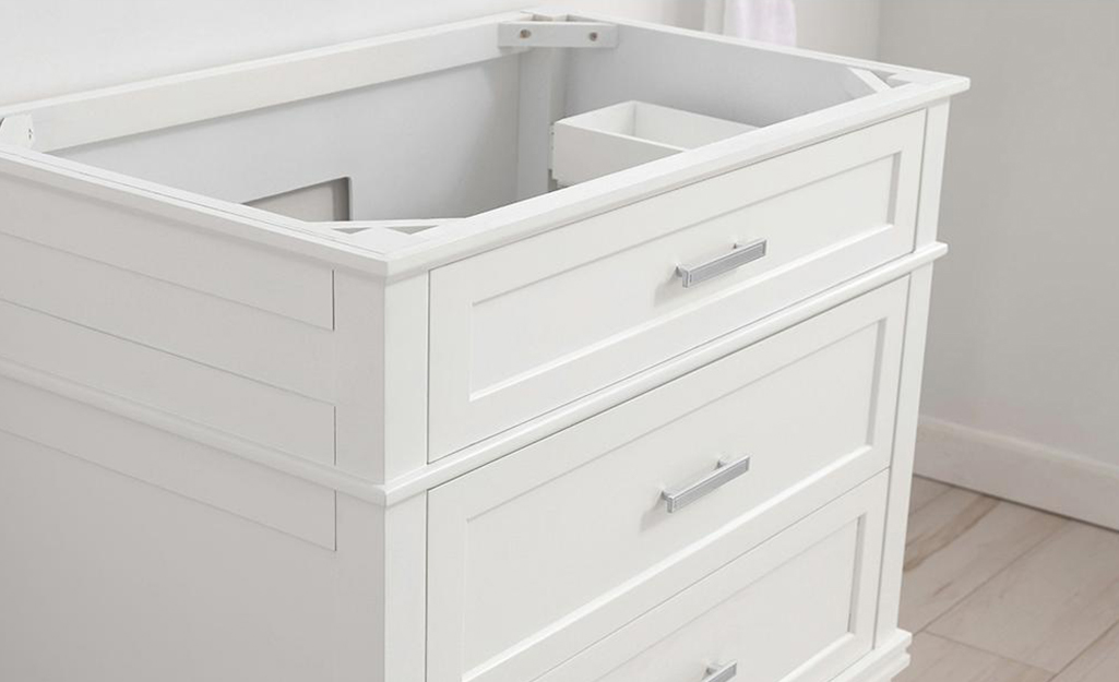 A white bathroom vanity without a countertop or sink.