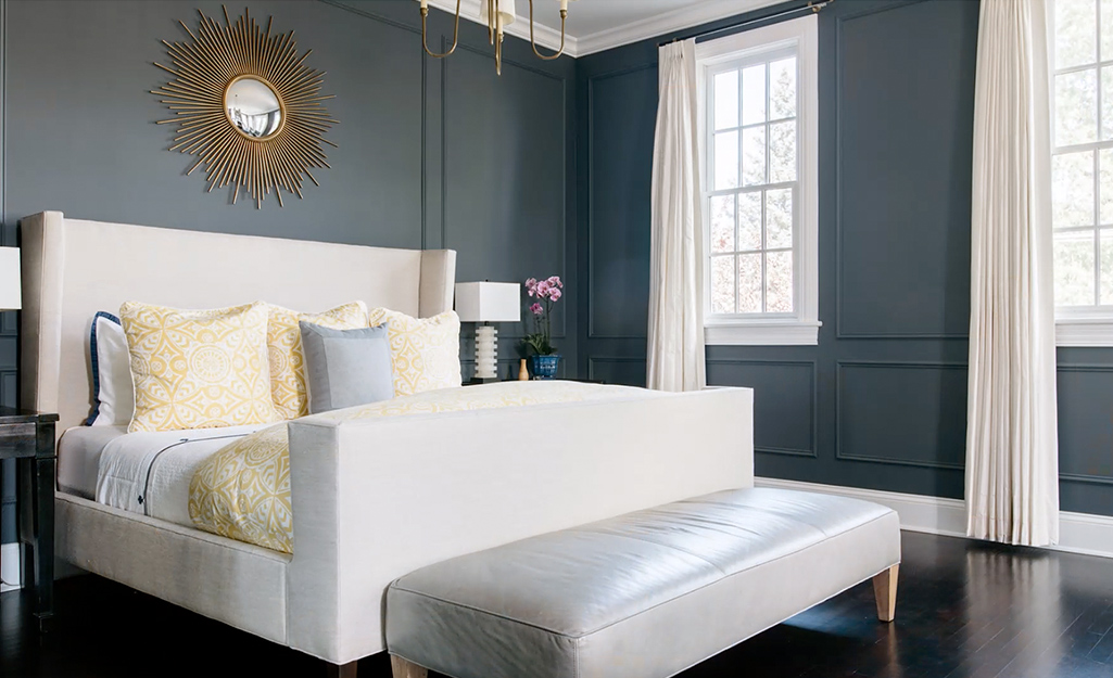 A bedroom with an upholstered king bed and white leather bench. 