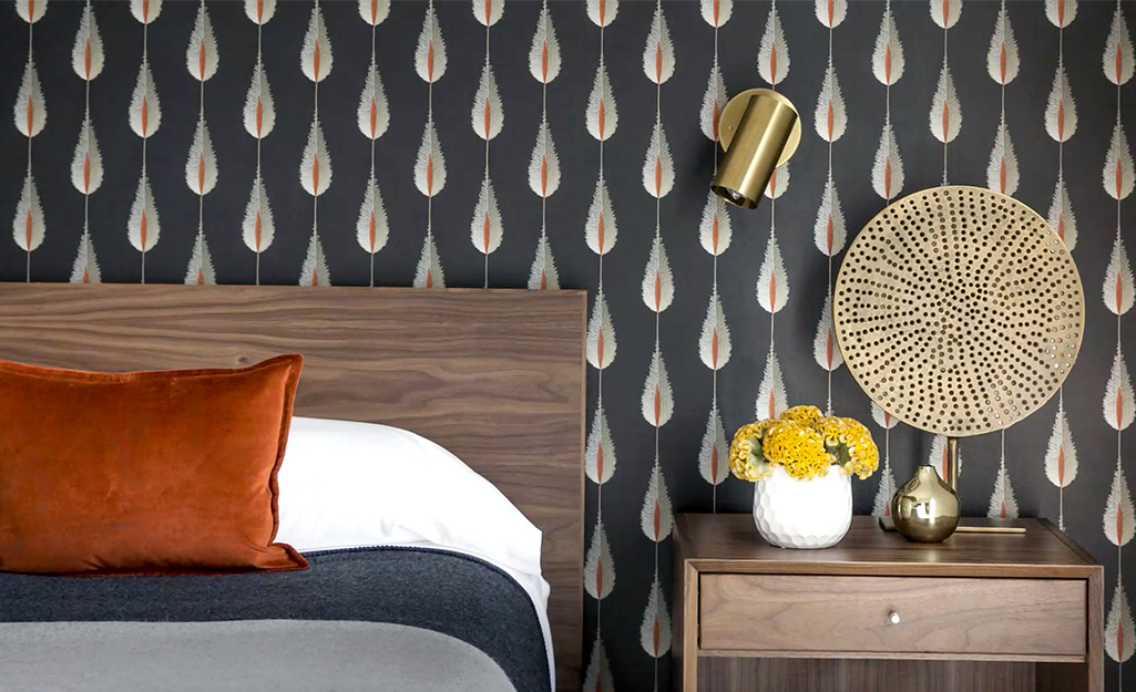 A primary bedroom featuring a dramatic and graphic wallpaper in a stylized feather print.