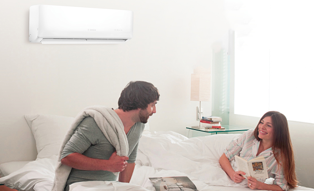 Two people in a room with a mini-split air conditioner installed.