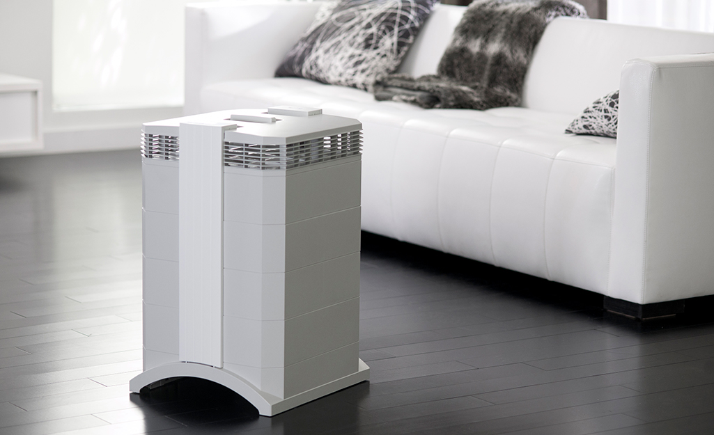 An air purifier in front of a sofa in a living space.