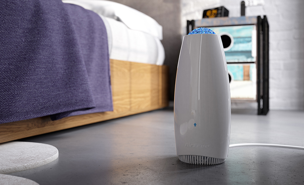 An air purifier next to a bed in a room.