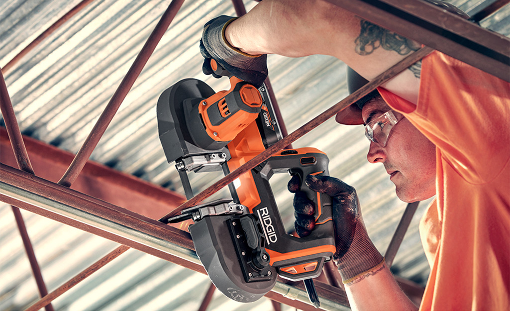 A man cuts metal with a band saw.