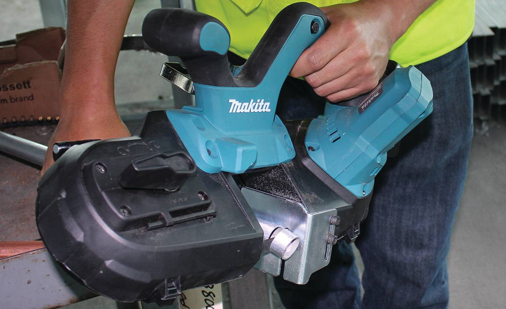 A man guides a band saw along a table top.