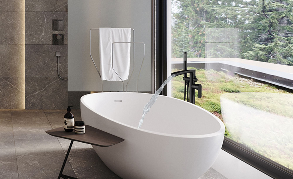 A tub faucet with a dark finish on a white porcelain tub.