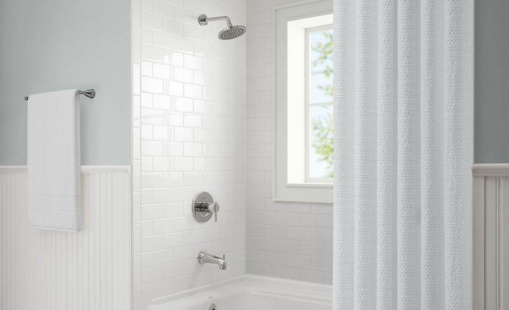 A shower faucet in a chrome finish in a white  bathroom.