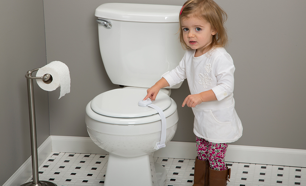 A child trying to get into a toilet with a child-lock lid.