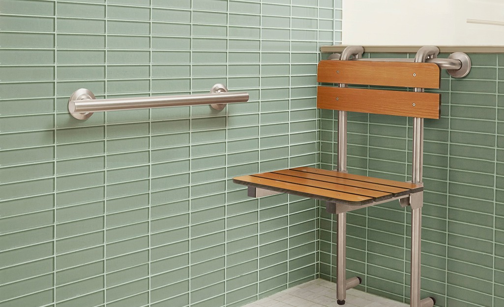 A bath chair and grab bar in a green shower.