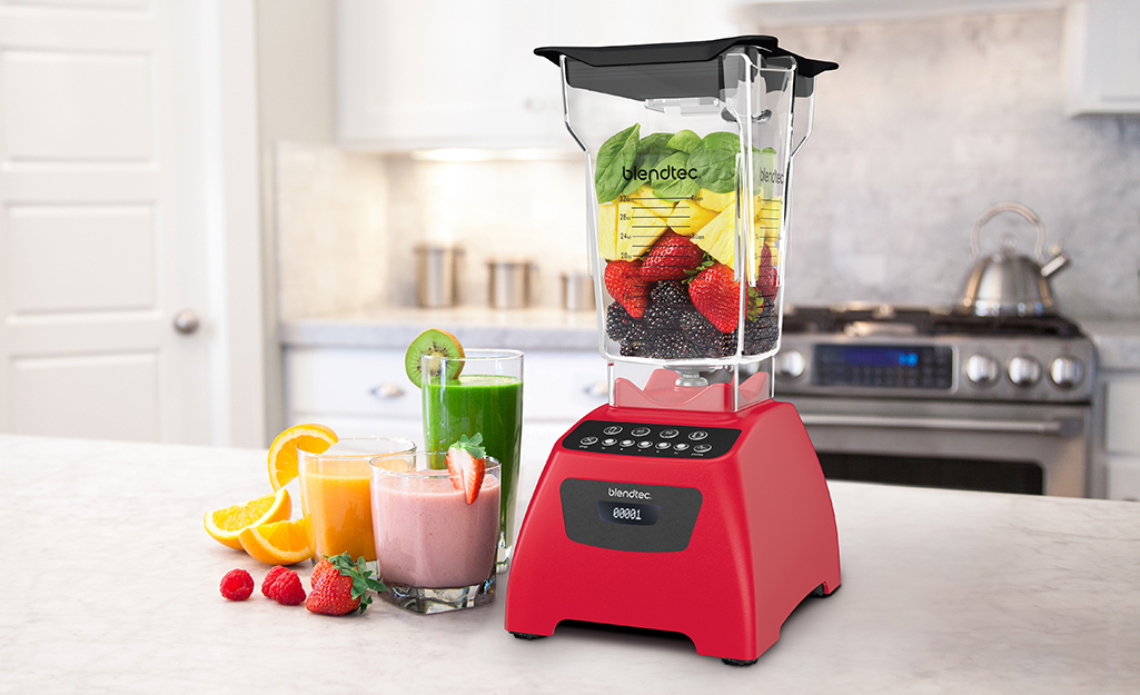 Larger countertop blender and three glasses filled with blended drinks.