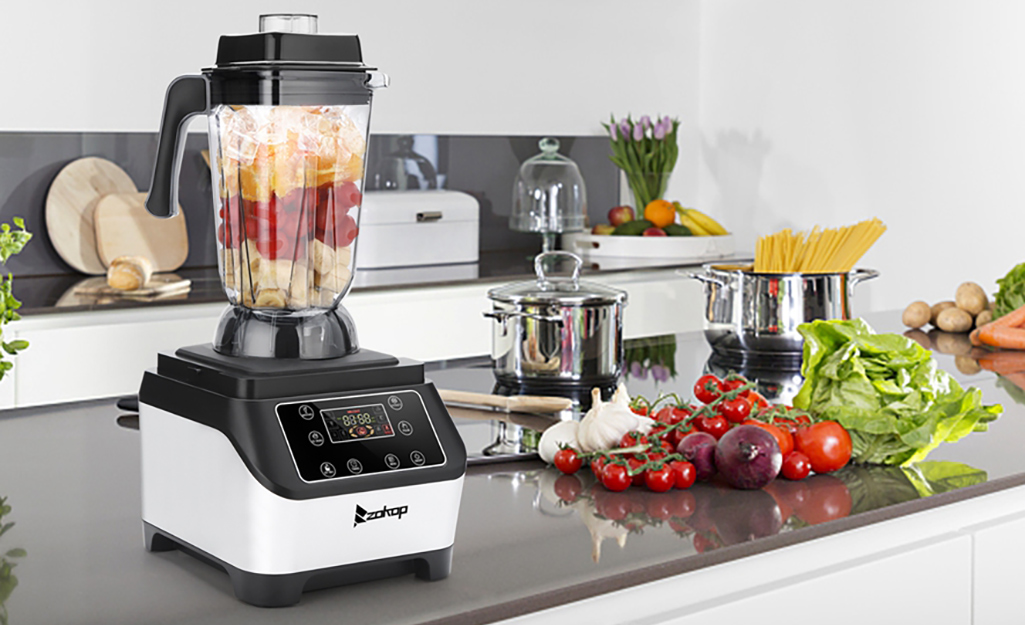 A countertop blender filled with ice cubes and topped off with strawberries.
