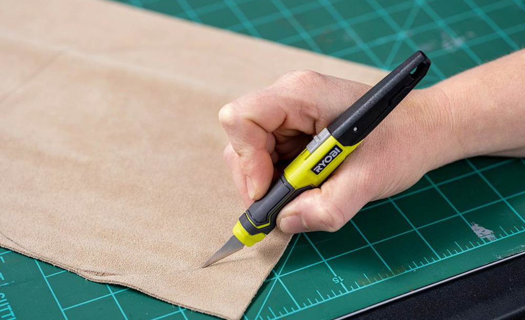 A person cuts fabric with a craft knife.