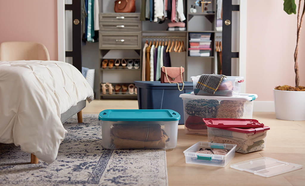 Plastic moving bins and storage totes are used to pack a bedroom closet.