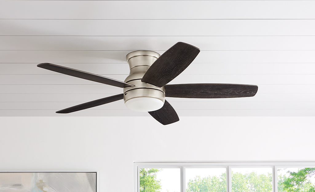 A ceiling fan installed on white shiplap.