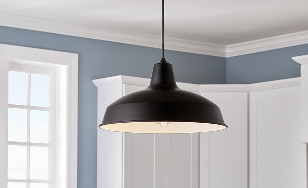 A black pendant light hangs in a kitchen.
