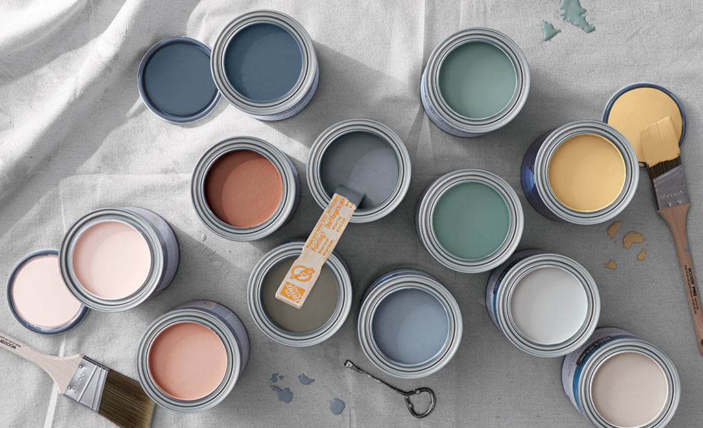 Open paint cans on a drop cloth displaying various paint colors.