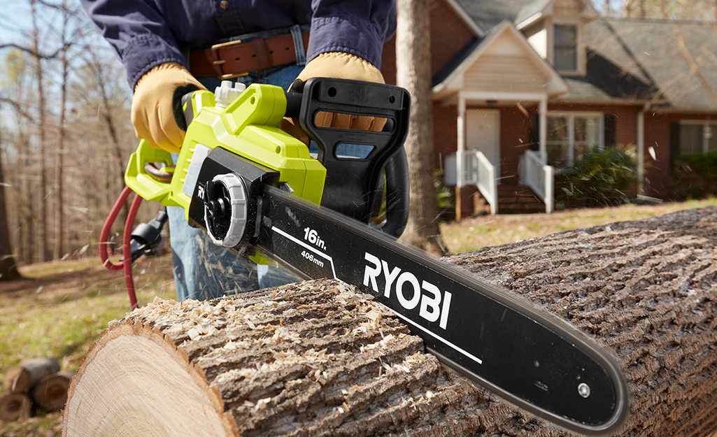 A person using a chainsaw to cut a large log.