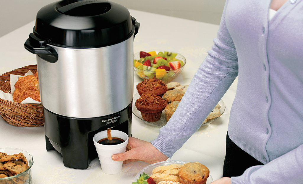 A person gets coffee from a coffee urn.
