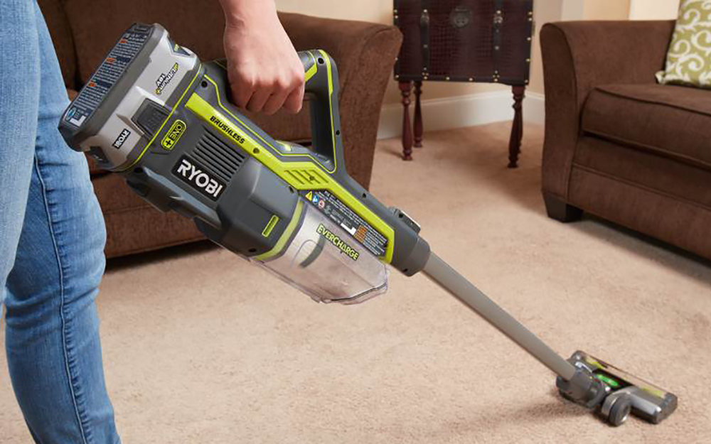 A person pushing a cordless vacuum on carpet A person pushing a cordless vacuum on carpet