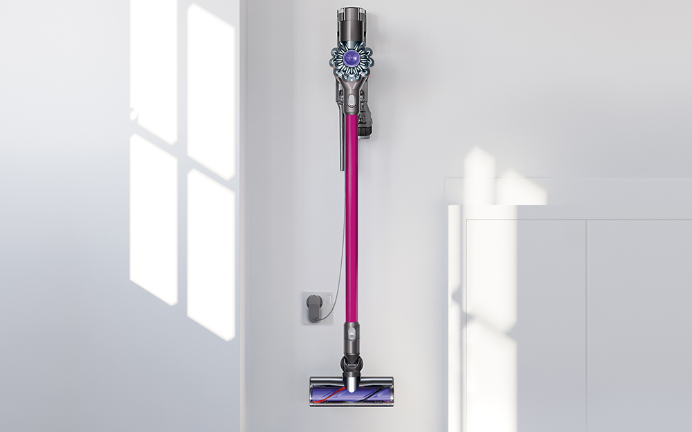 A cordless vacuum hanging on a holster on the wall