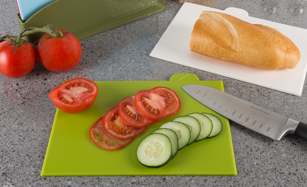Plastic and poly cutting boards with a chef's knife and food.