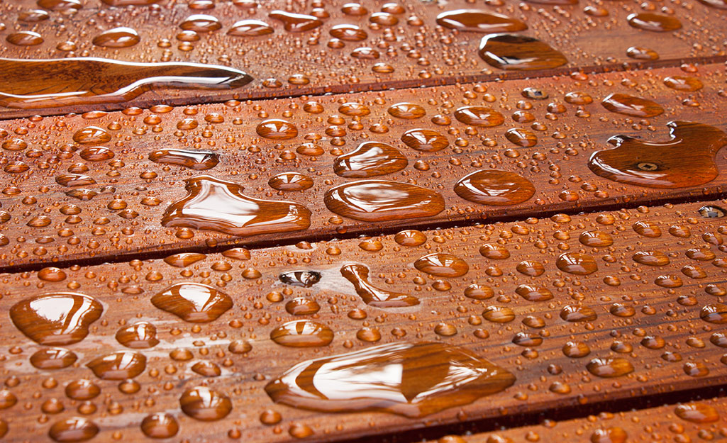 Water beads on a stained deck.