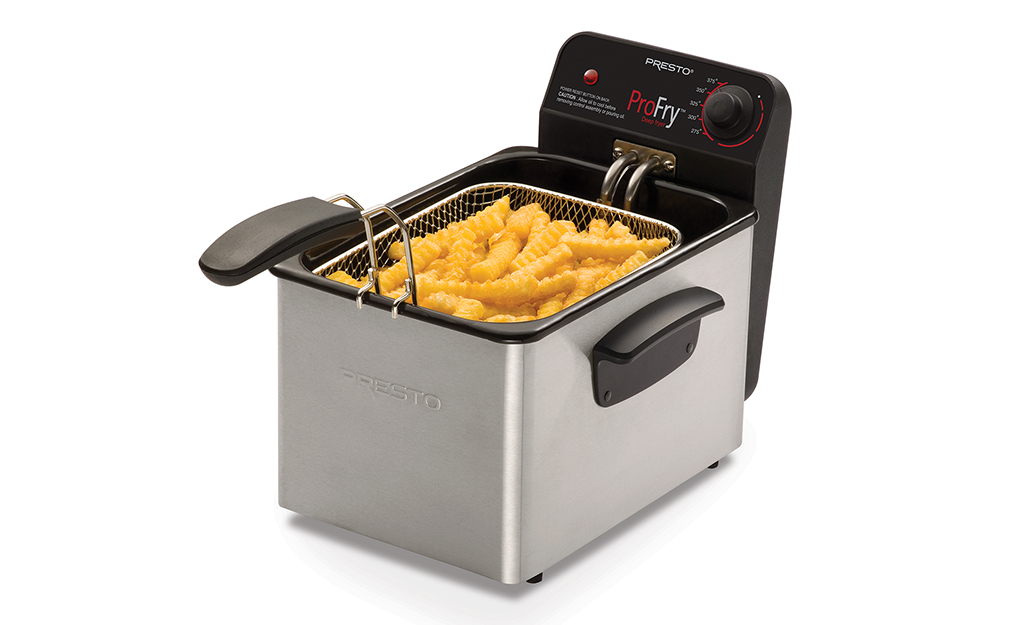 A deep fryer with a basket full of cooked French fries.