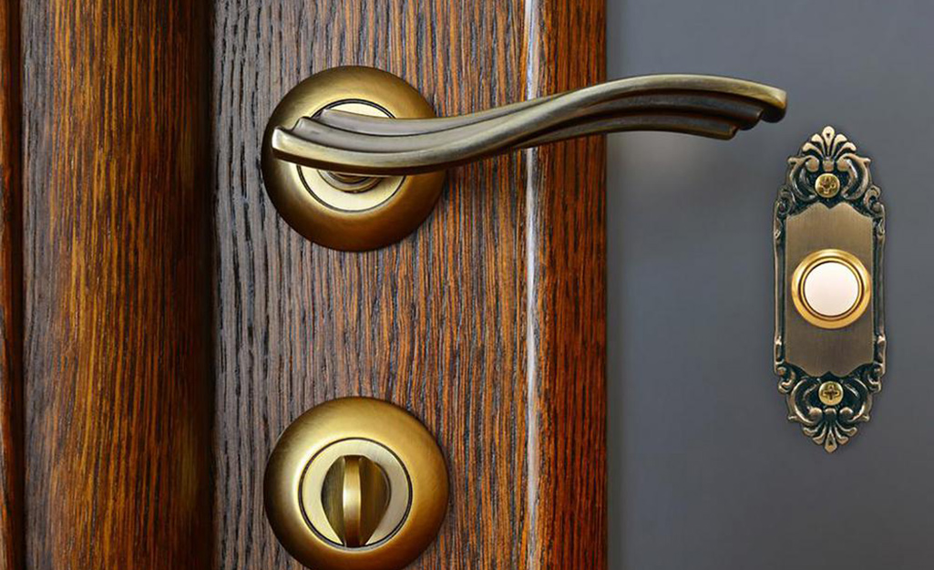 An ornate wired doorbell next to a front door handle.