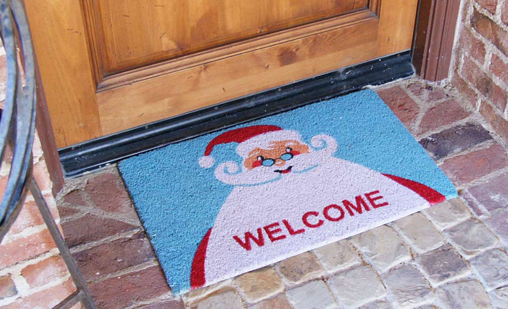 A boot scraper placed next to a holiday-themed doormat.