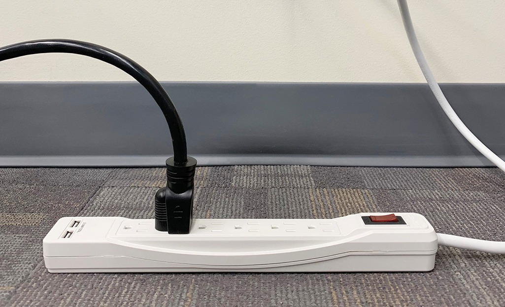A white surge protector featuring a black cord.