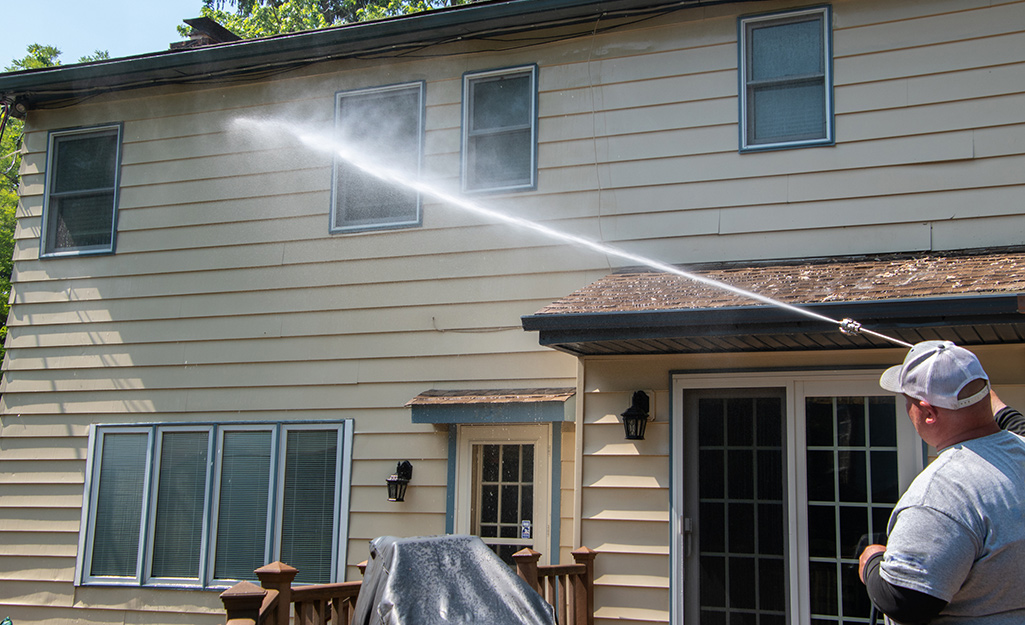 A man pressure washing the exterior of a home.