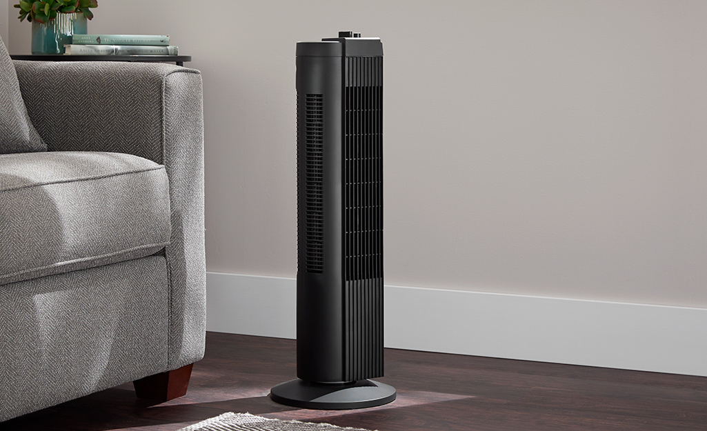 A tower height floor fan in a room.