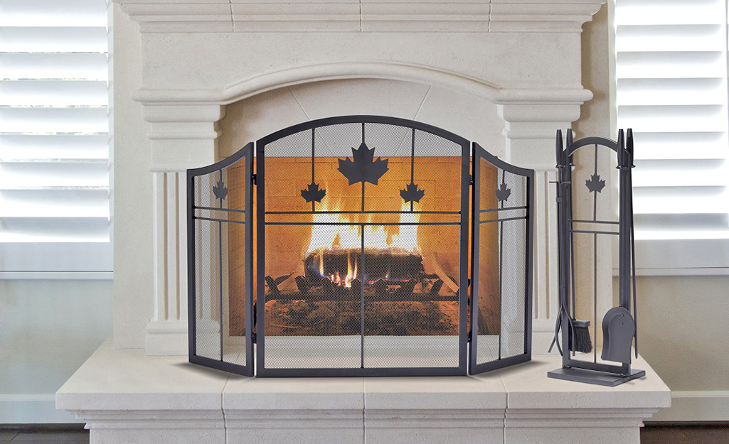 A fireplace screen in front of a lit fireplace.
