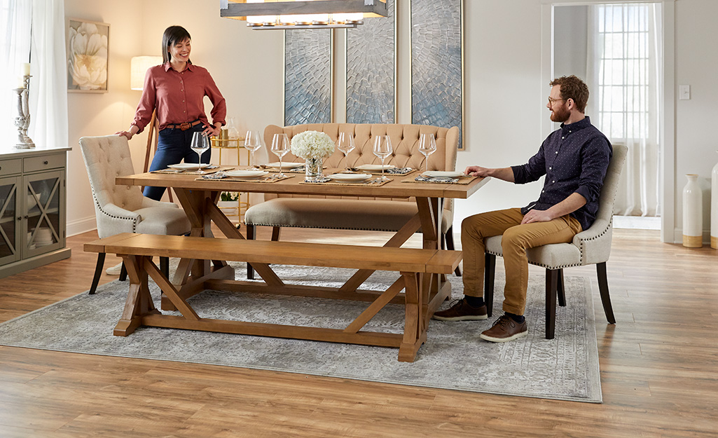 Two people in a dining room with laminate wood flooring.
